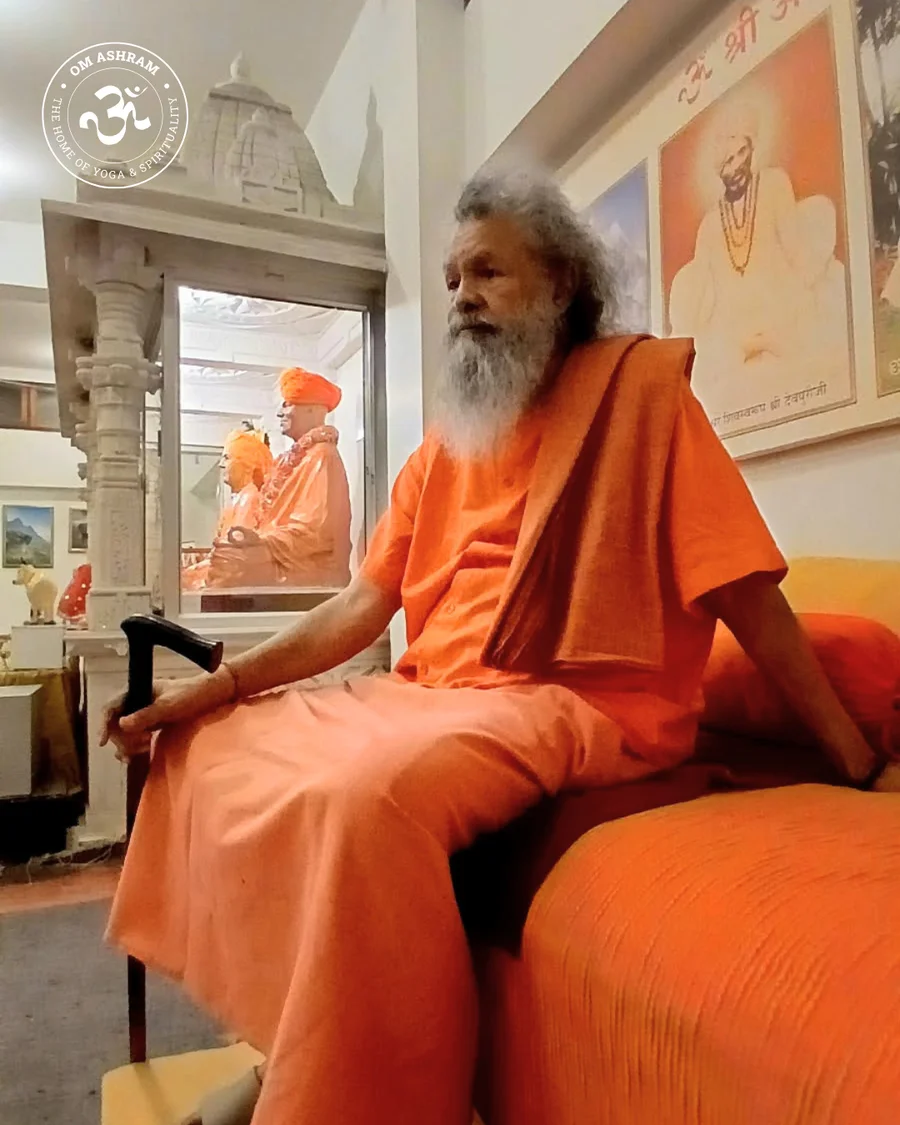 Shree Vishwaguru Ji seated with the portraits of the holy Masters of Shree Alakhpuri Ji Siddha Peeth parampara in the background.